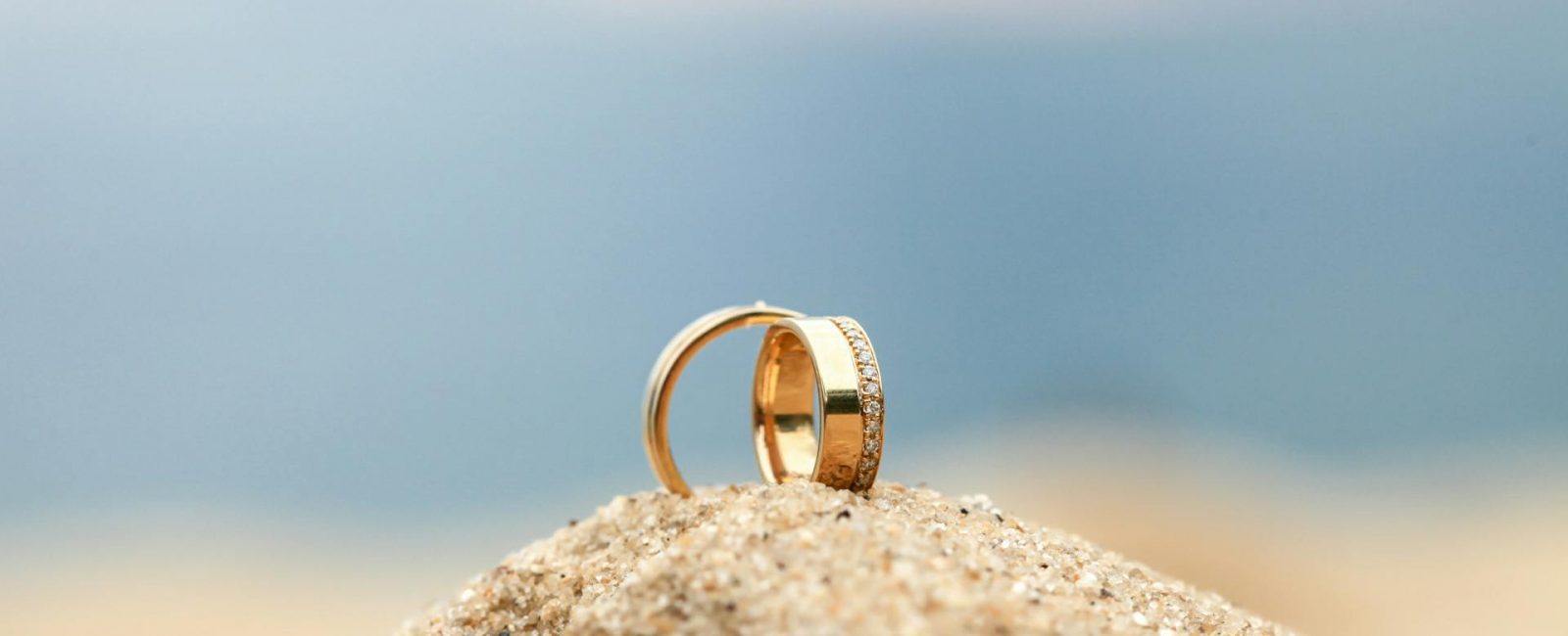 two wedding bands sitting on a sand mound